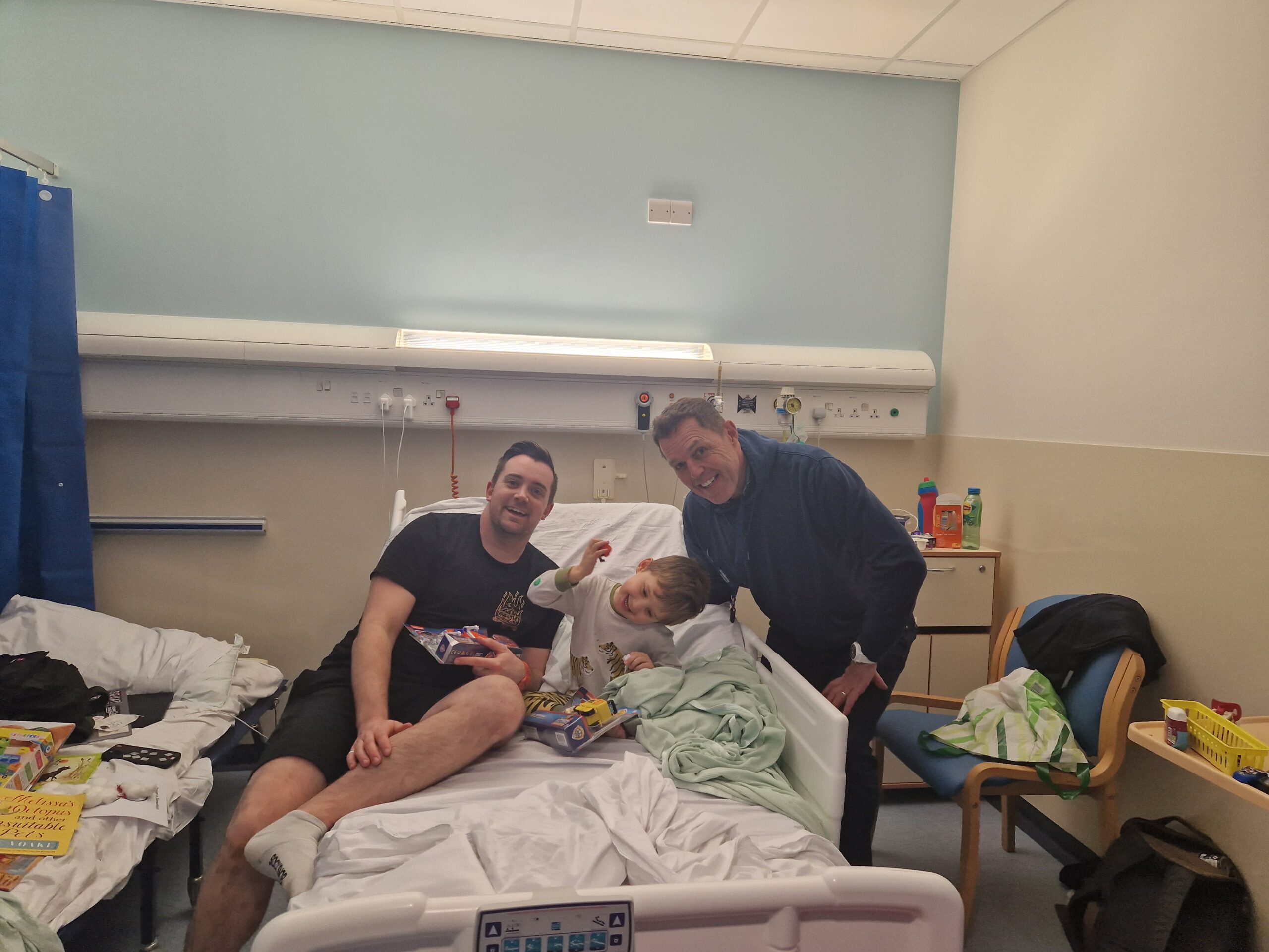 Andrew Harman posing with a patient and their dad in Ward 3.