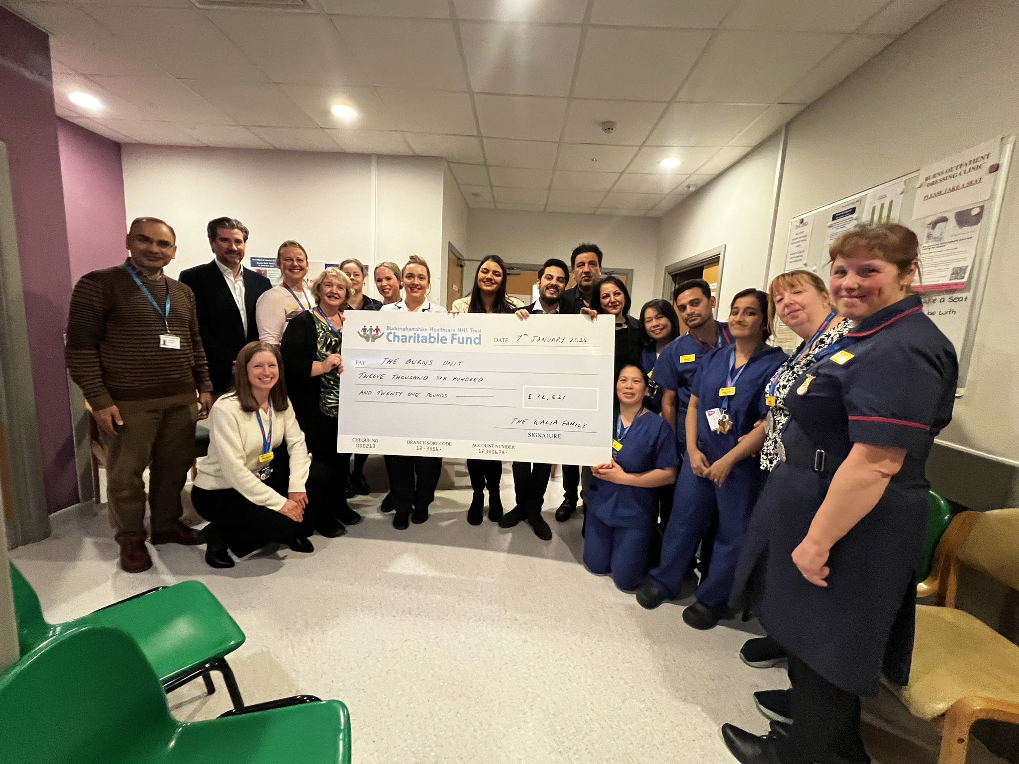 The Walia Family holding a larger cheque with a great number of Burns Unit staff and Trust Management,