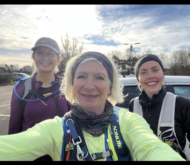 Jacqui wearing some winter running equipment, flanked by two friends during a run.