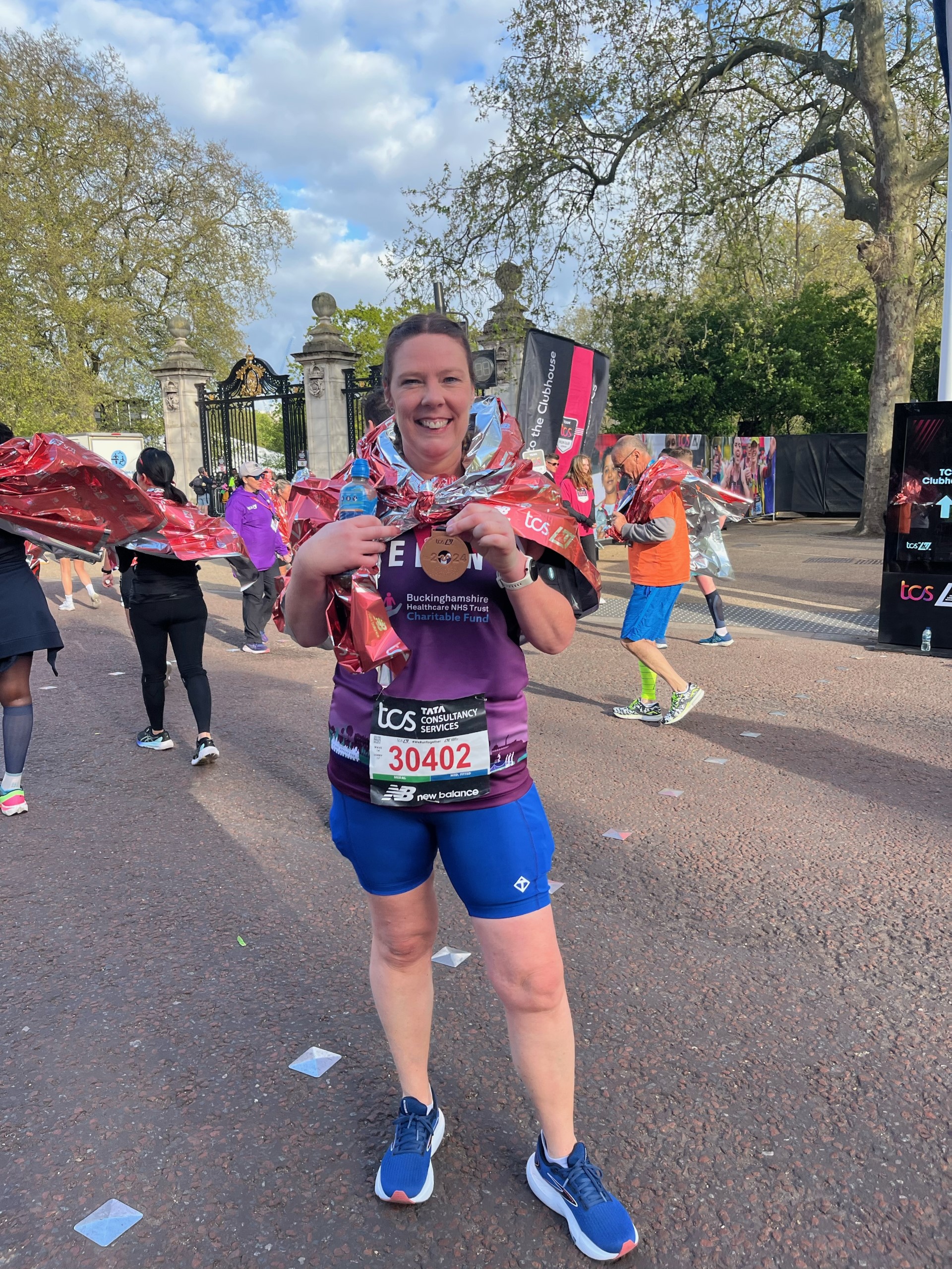 Helen Holding her London Marathon Medal wearing a purple Buckinghamshire Healthcare NHS Trust Charitable Fund running vest